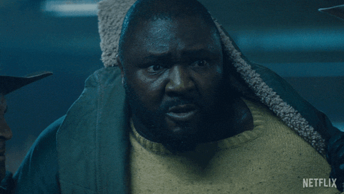 a man in a green jacket and yellow sweater has a netflix logo on the bottom right
