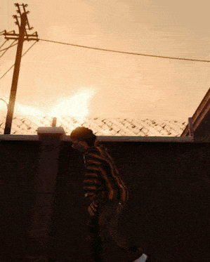 a man in a striped shirt stands on a wall