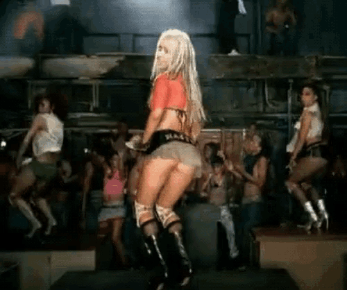 a woman in a red top and short skirt is dancing in front of a crowd
