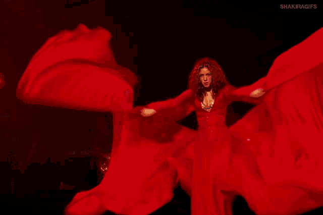 a woman in a long red dress is dancing on stage .