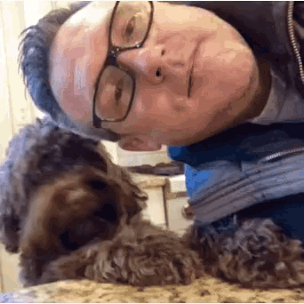 a man wearing glasses is laying down with a dog