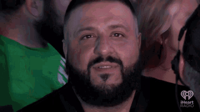 a man with a beard is sitting in a crowd of people at a concert .