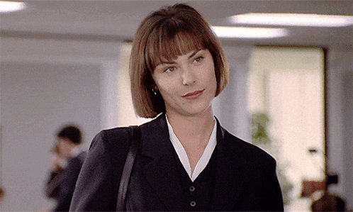 a woman in a black suit with a white collar and buttons