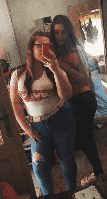 two girls are taking a selfie in front of a mirror with one wearing a shirt that says love