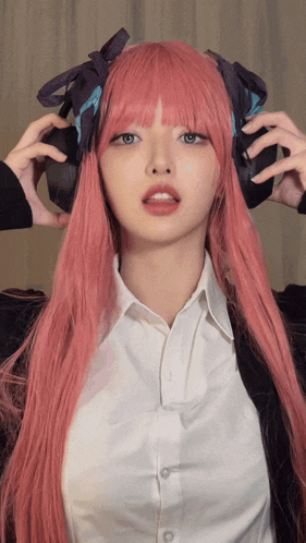 a woman with pink hair is wearing headphones on her head