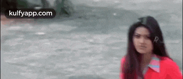 a woman is standing in front of a body of water looking at the camera .