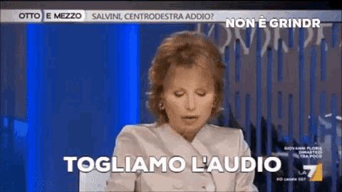 a woman is sitting in front of a screen that says togliamo l' audio .
