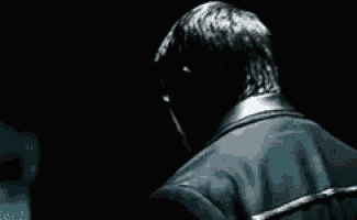 a man in a leather jacket is standing in the dark and looking at something .