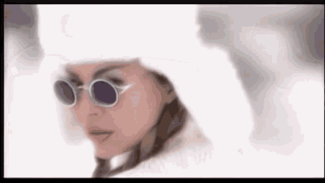 a close up of a woman wearing sunglasses and a hat in the snow .