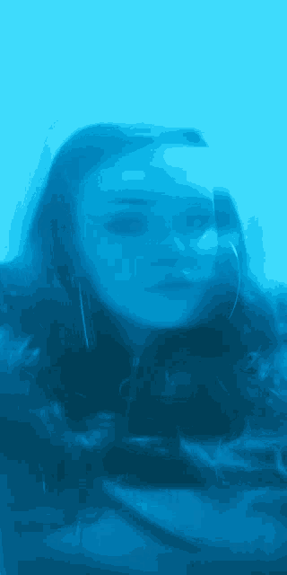 a blurry picture of a woman 's face is against a blue background