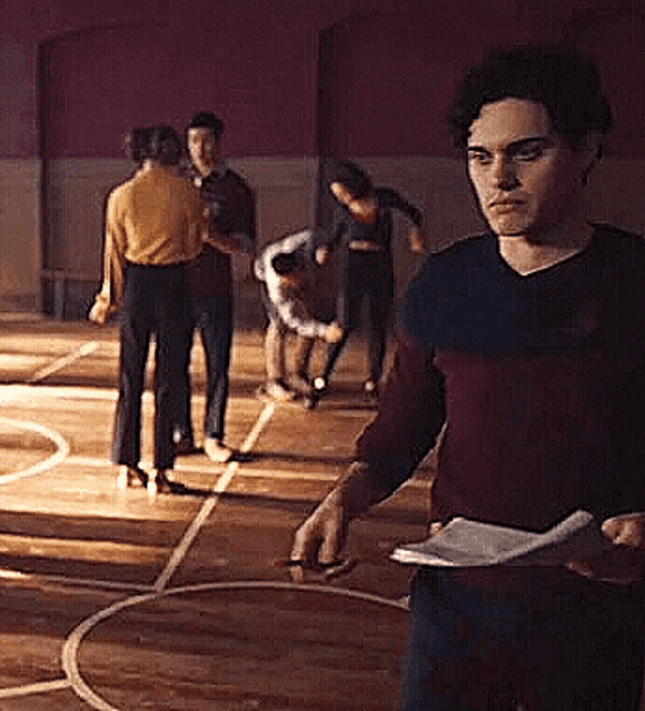 a man is standing in a gym holding a piece of paper in his hand