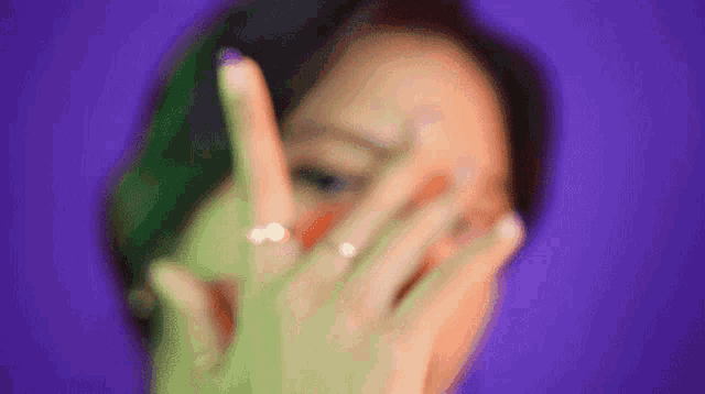 a close up of a woman covering her face with her hands .