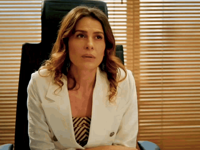 a woman in a white jacket sits in a chair