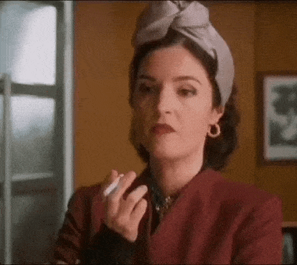 a woman in a headband is smoking a cigarette .
