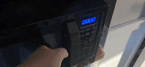 a person is pressing a button on a microwave that says 00 : 013