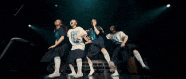 a group of people are dancing on a stage in front of a crowd .