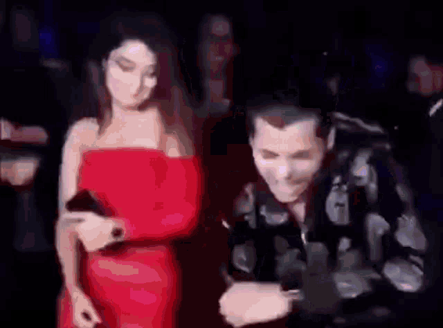 a man and a woman are standing next to each other at a party .