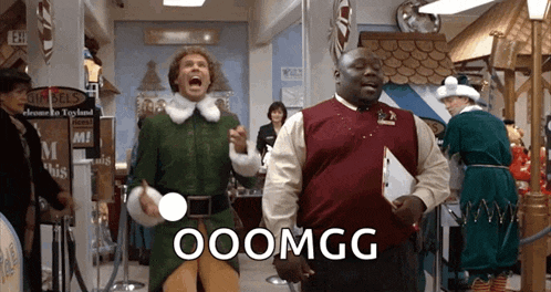 a man in a green elf costume is standing next to a man in a red vest with the words ooomgg written on it