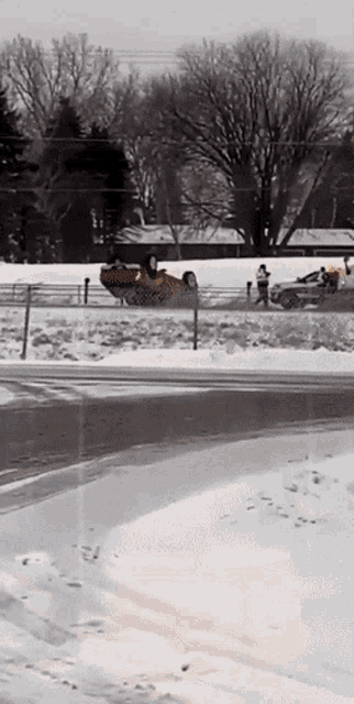 a car is upside down on the side of a snowy road