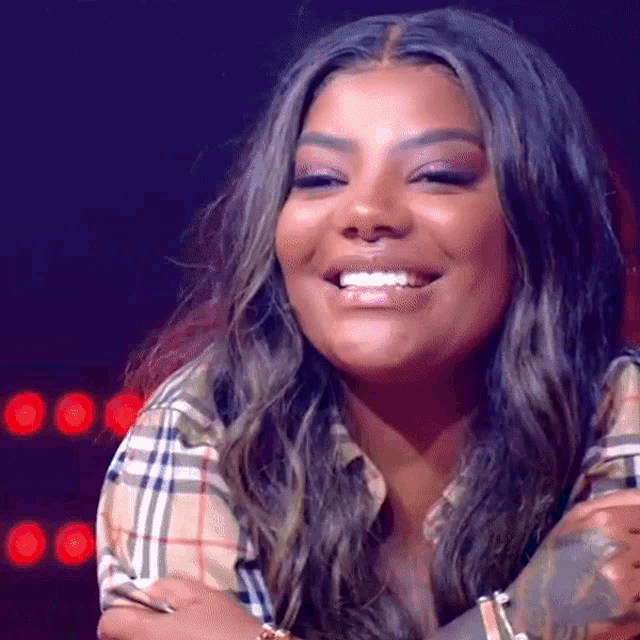 a woman wearing a plaid shirt is smiling and looking to the side