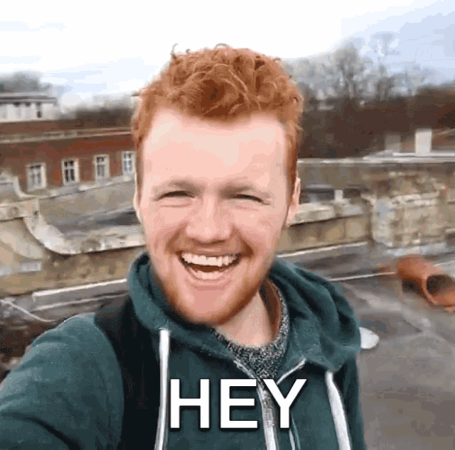 a man with red hair and a green hoodie says " hey "