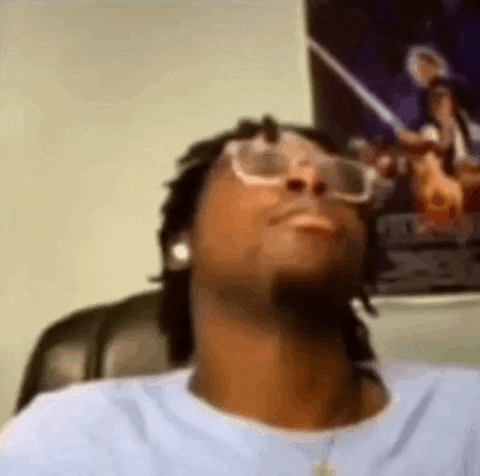 a man wearing glasses and ear buds is sitting in a chair .