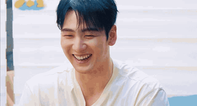 a man with blue hair and a white shirt is smiling
