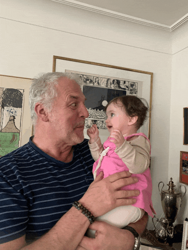 a man in a striped shirt is holding a baby girl
