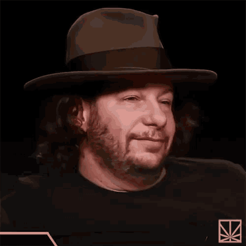 a man with a beard wearing a fedora and a black shirt