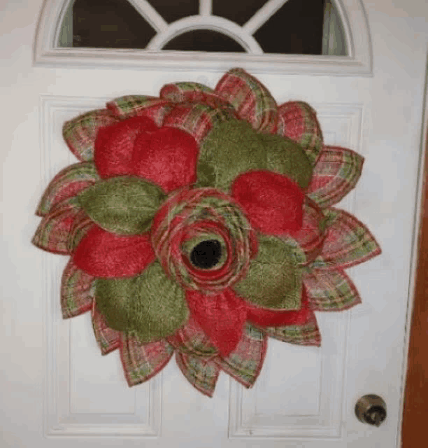 a red and green wreath hangs on a door