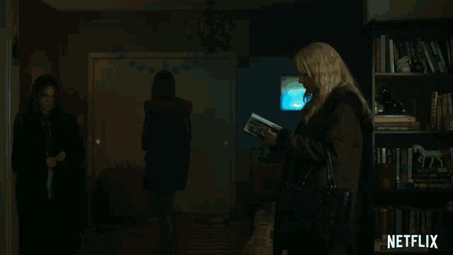 a woman reading a book in a dark room with a netflix logo in the corner