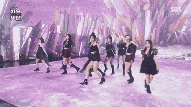 a group of women are dancing on a stage with a purple background .