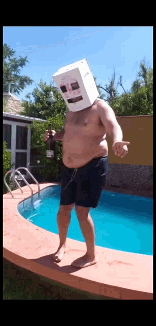 a man wearing a cardboard box on his head holds a bottle of beer