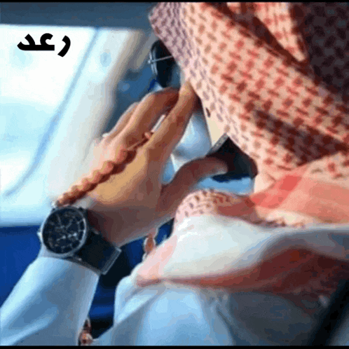 a man wearing a scarf and a watch is talking on a phone
