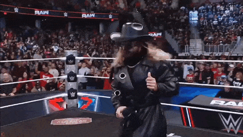 a man in a cowboy hat is standing in a wrestling ring ..