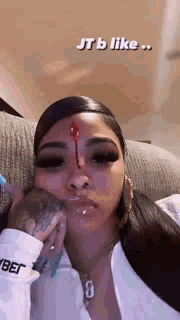 a woman with a bloody nose is sitting on a couch with her hand on her face .