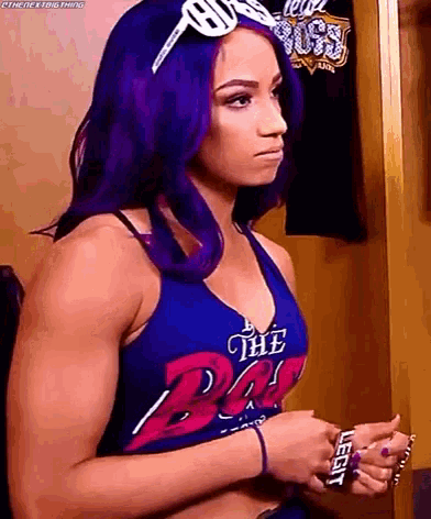 a woman with purple hair is wearing a blue tank top with the word the boss on it .