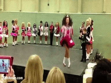 a woman is taking a picture of a group of dancers with gifsforum.com in the lower right corner