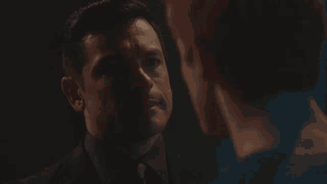 a man in a suit and tie is talking to another man