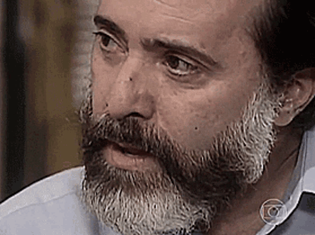 a close up of a man with a beard and a g on his neck