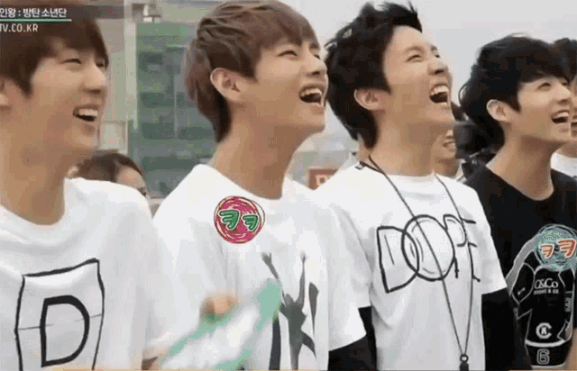 a group of young men are laughing and one of them has a dope shirt on