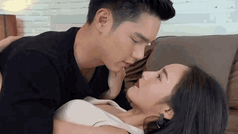 a man is kissing a woman on the neck while laying on a bed .