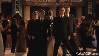 a little girl is standing in front of a group of men in suits .