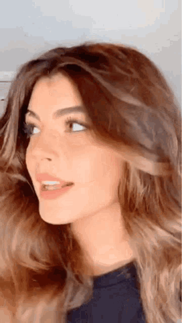 a close up of a woman 's face with her mouth open and her hair blowing in the wind .