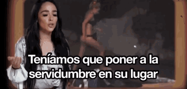 a woman is standing in front of a sign that says tener a la servidumbre en su lugar