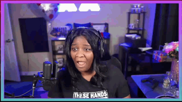 a woman wearing headphones and a shirt that says `` these hands '' is sitting in front of a microphone