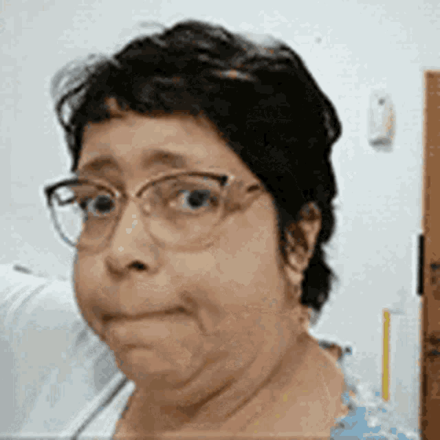 a woman wearing glasses is making a funny face and making a funny face .