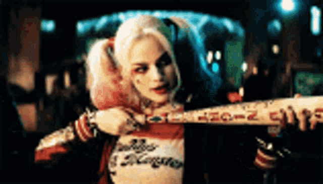 a woman in a suicide squad costume is holding a bat in her hand .