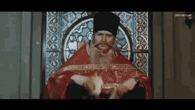a man with a beard in front of a stained glass window that says ntv