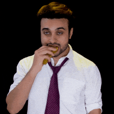a man wearing a white shirt and a purple tie eating something